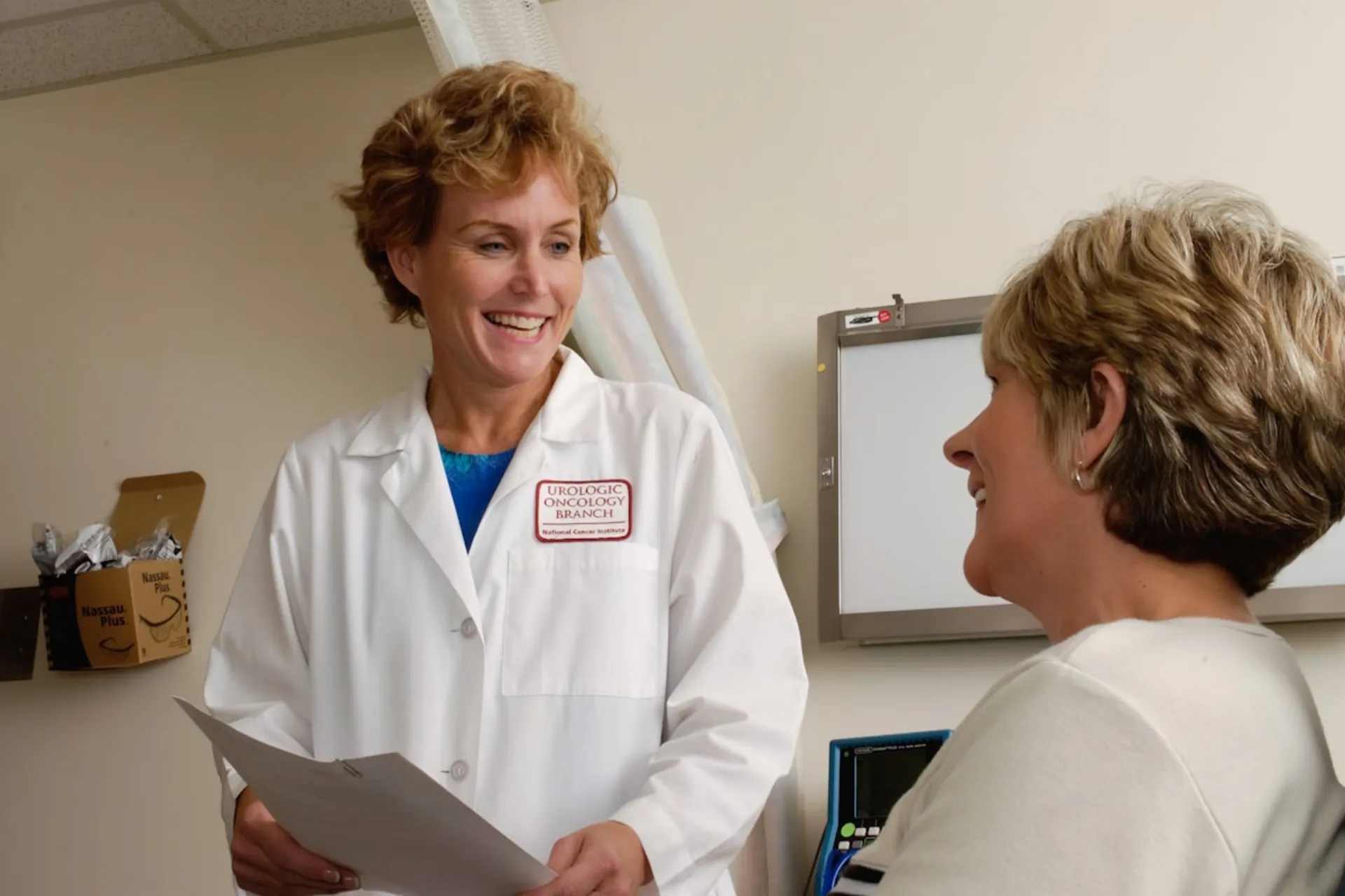 A clinician reviewing paperwork with a patient at the front desk