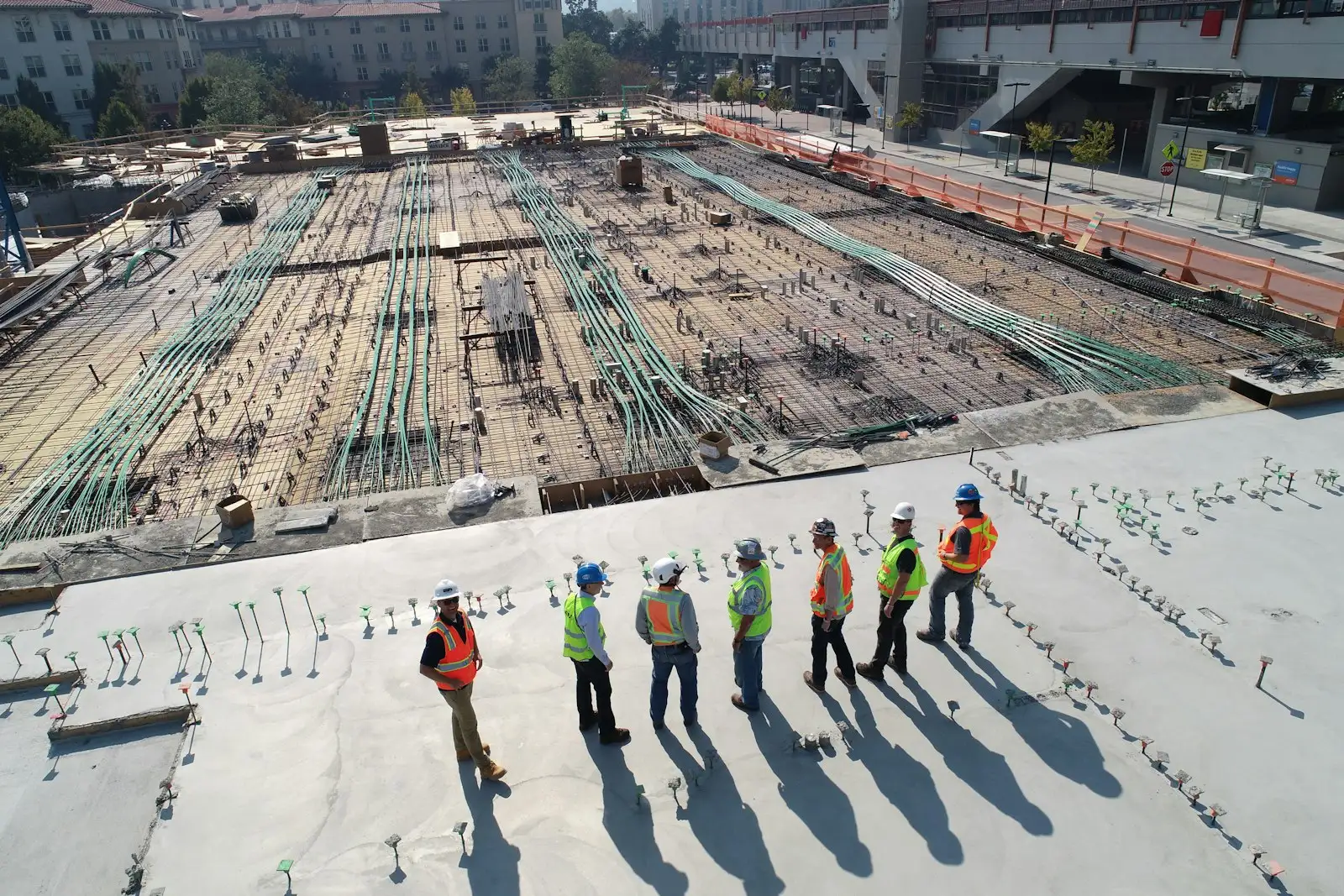 A construction crew in safety vests surveying a new building site from above